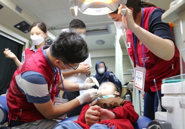 송인석 안암병원 치과 교수(왼쪽 )가 아프간 어린이를 치료하고 있다.