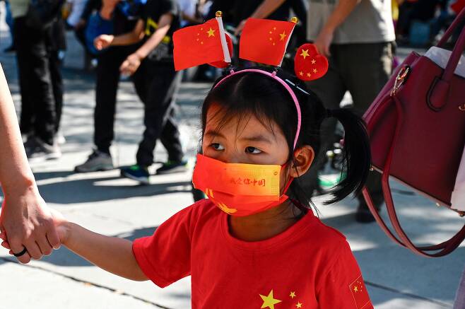 중국 국경절을 맞은 지난 1일 베이징에서 빨간 옷을 입은 어린 아이가 부모 손을 잡고 거닐고 있다. /AFP연합뉴스