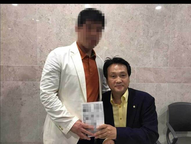 조폭 출신 인사 A씨가 안민석 민주당 의원과 함께 찍은 사진. 이들이 들고 있는 책은 안 의원이 쓴 박근혜 정부 비판 서적이며, 2018년 출간됐다. /페이스북