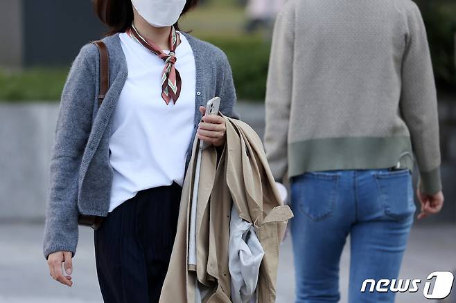일교차가 큰 날씨가 이어진 20일 오전 서울시내에서 한 시민이 외투를 들고 걷고 있다. 2021.10.20/뉴스1 © News1 조태형 기자