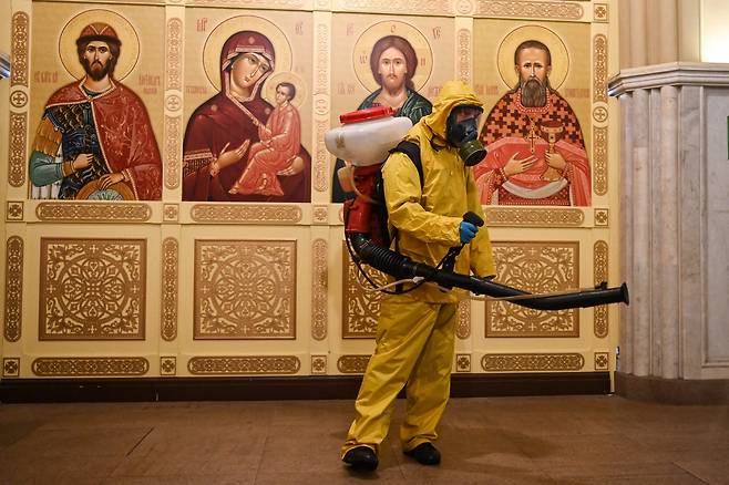 19일(현지 시각) 러시아 보건 당국 관계자가 마스크를 쓰고 모스크바의한 역사를 소독하고 있다./AFP 연합뉴스