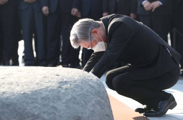 이재명 더불어민주당 대선 후보가 22일 오후 경남 김해시 진영읍 봉하마을 노무현 전 대통령 묘역을 참배하며 앉아 너럭바위를 만지고 있다. 연합뉴스