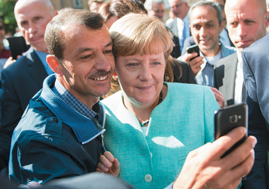 앙겔라 메르켈 독일 총리가 지난 2015년 베를린의 ‘난민 접수 구역’에서 한 이라크 난민과 포즈를 취하고 있는 모습. 그해 메르켈은 100만 명 가까운 중동 난민의 독일 입국을 허용했다. 모비딕북스 제공