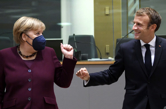 독일 총리 직을 물러나기 전에 유럽연합(EU)의 마지막 정상회의에 참석한 앙겔라 메르켈(왼쪽)이 22일(현지시간) 에마뉘엘 마크롱 프랑스 대통령과 주먹을 맞대며 웃고 있다.브뤼셀 풀 기자단 AP 연합뉴스
