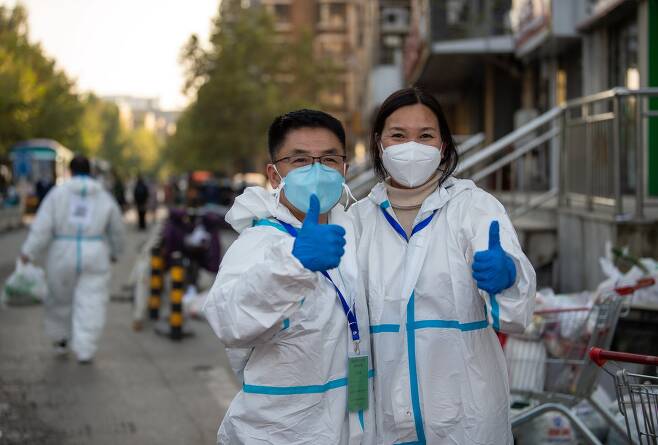 홍푸유안 주택단지 주민인 멩수에(왼쪽)과 그의 아내가 23일 방역복을 입고 코로나 방역 자원봉사자로 나섰다. 신화사=연합뉴스