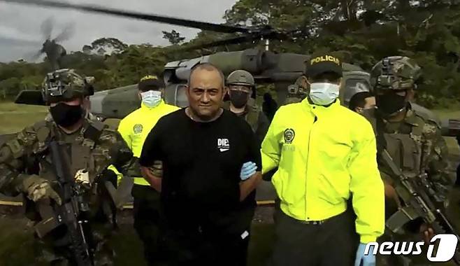 콜롬비아 최대 마약 밀매업자 다이로 안토니오 우스가(50)가 군경에 붙잡힌 채 걸어가고 있다. 2021.10.23 © AFP=뉴스1