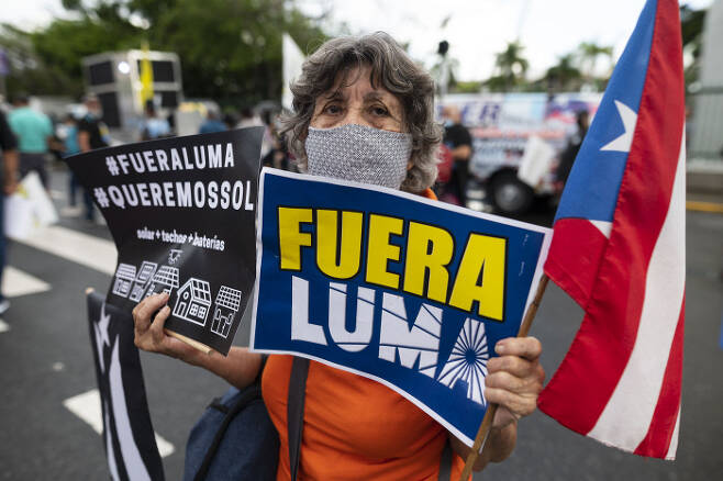 미국령 푸에르토리코의 한 시민이 지난 15일 민간 전력회사인 루마에 항의하기 위해 스페인어로 “루마는 나가라”라고 적힌 손팻말을 들고 행진하고 있다. 푸에르토리코｜AP연합뉴스