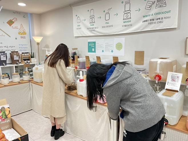 지난 19일 찾은 서울 강남구 소재 제로웨이스트 상점인 ‘덕분애’ 진열대의 모습. 상점을 방문한 손님들이 세탁 세제와 섬유유연제를 리필하고 있다.