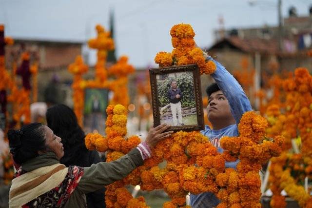 1일 멕시코 미초아칸 주의 아로쿠틴 묘지에서 친척들이 사랑하는 사람의 무덤 옆에서 밤을 보낼 준비를 하면서 제단을 쌓고 있습니다. AP 뉴시스