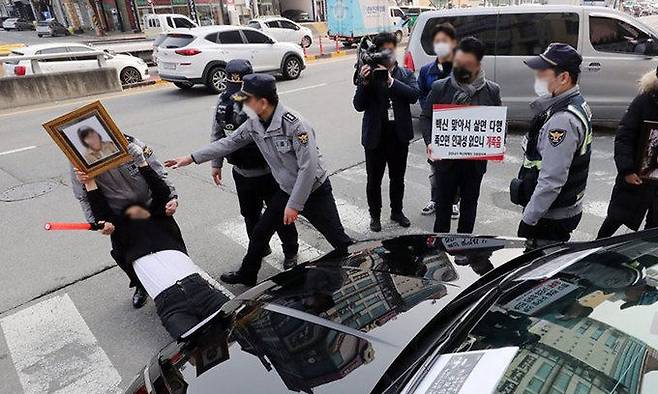 19일 정은경 질병관리청장이 코로나19 추가 접종을 하고 병원을 나서자 백신피해자가족협의회원들이 항의하며 차량을 막아서고 있다. 연합뉴스