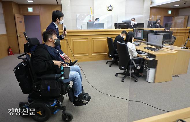 지난 10월 19일 서초구 서울행정법원에서 열린 보조기기(전동 휠체어) 급여 거부 처분 취소소송 공개변론에서 원고측 법률대리인이 전동휠체어를 사용 중인 장애인들과 함께 장비 시연을 하고 있다./ 김기남 기자