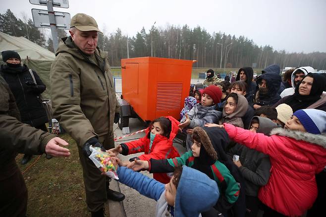 지난 17일(현지 시각) 폴란드와 국경을 접한 벨라루스 그로드노주 '브루즈기-쿠즈니차' 검문소에서 노숙하는 중동 출신 난민 아이들이 구호 식품을 받기 위해 몰려들고 있다. 이들은 전쟁과 빈곤을 피해 중동에서 벨라루스로 들어왔으며, 유럽연합(EU) 회원국인 폴란드로 들어가 선진국에서의 새 삶을 꿈꾼다. /로이터 연합