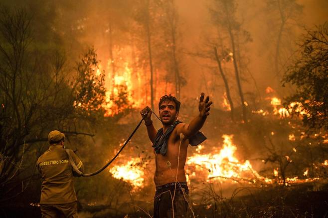 지난 8월 그리스에서 두번째로 큰 섬인 에비아섬에서 발생한 산불을 진화하려 나선 주민이 물을 다 써서 빈 호스를 들고 있다. AFP=연합뉴스