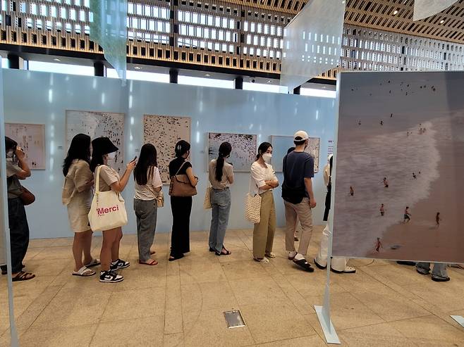 Visitors view the exhibition “Photographs by Yosigo: Holiday Memories” at Ground Seesaw Seochon in Seoul. (Park Yuna/The Korea Herald)