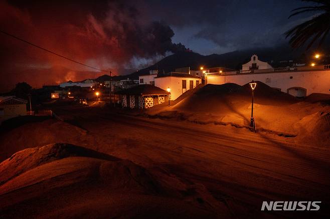 [라팔마=AP/뉴시스] 6일(현지시간) 스페인 카나리아제도 라팔마섬의 쿰브레 비에하 화산에서 용암이 흘러나오면서 라스 만차스 마을 거리와 가옥이 화산재로 덮여 있다. 2021.12.08.