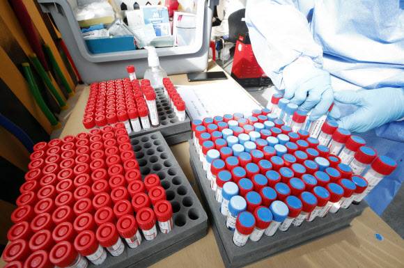 선별진료소에 쌓여가는 검체통 - 코로나19 일일 확진자가 이틀 연속 7천명을 넘어선 9일 오전 광주 북구 선별진료소에서 보건소 의료진이 수거한 검체 통의 수량을 확인하고 있다. 2021.12.9 광주 북구청 제공