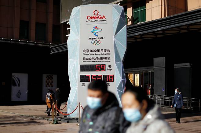 미국이 베이징 동계올림픽에 대해 '외교적 보이콧' 방침을 밝힌 가운데 7일 중국 수도 베이징에서 올림픽이 59일 앞으로 다가왔음을 알리는 카운트다운 시계 앞을 마스크를 쓴 행인이 지나고 있다. /로이터 연합뉴스