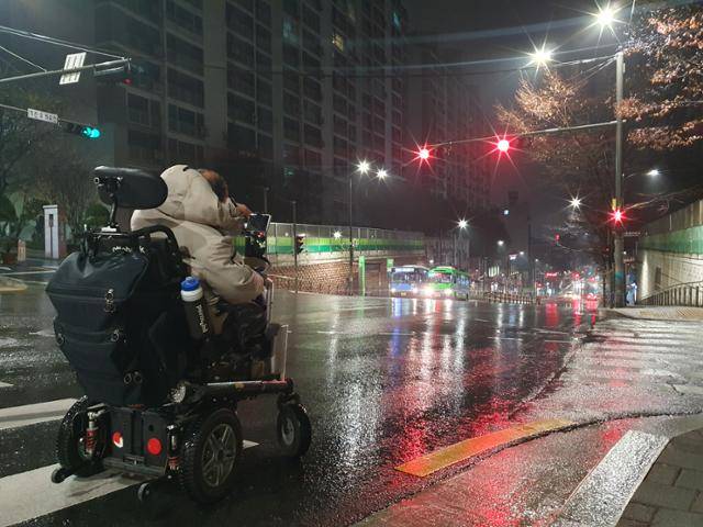 15일 새벽, 뇌병변 장애인 이규식씨가 서울 혜화역 장애인 이동권 선전전 참여를 위해 집을 나서고 있다. 그의 집 근처의 인도가 좁아 이씨의 휠체어는 차도로 다닐 수밖에 없었다. 전혼잎 기자