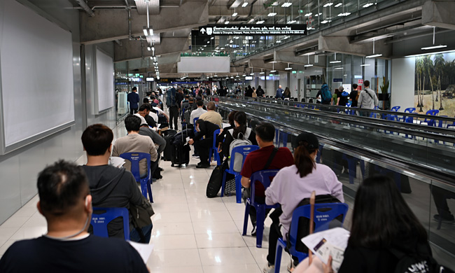 태국 방콕의 수완나품 공항에 내린 승객들이 의자에 앉아 공항직원의 지시대로 PCR 검사 결과지와 백신접종증명서 등의 서류를 꺼내놓고 입국심사를 기다리고 있다.