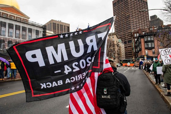지난 5일(현지시간) 미국에서 백신 접종 의무화를 반대하는 시위자가 미국 국기와 트럼프 지지 깃발을 들고 걷고 있다. [AFP=연합뉴스]
