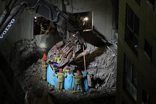 광주 화정 아이파크 붕괴 사고 나흘째인 14일 건물 지하 1층에서 구조대원들이 실종자 1명을 들어올리고 있다. 연합뉴스