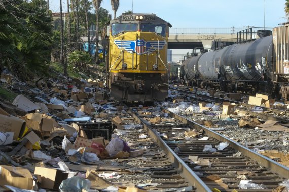 미국 로스앤젤러스(LA) 시내의 유니언퍼시픽 철로에 약탈된 화물의 빈 상자들이 널려 있는 가운데 14일(현지시간) 화물열차가 지나가고 있다. AP뉴시스