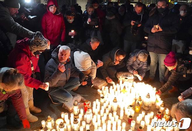 폴란드 바르샤바에서 사람들이 신종 코로나바이러스 감염증(코로나19)으로 죽은 사람들을 추모하기 위해 촛불을 켜고 있다. 2022.01.11 © AFP=뉴스1