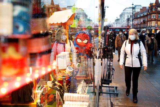지난달 27일 영국 런던에서 코로나19 확산 방지를 위해 마스크를 쓴 한 여성이 기념품 판매점 앞을 지나고 있다. 런던=AP 뉴시스