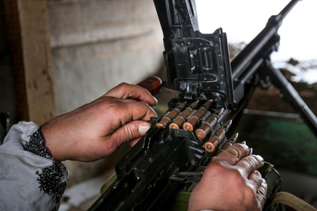 25일 우크라이나 동부 루한스크 지역 슬라비아노세르브스크에서 한 의용군이 기관총에 탄알을 장전하고 있다. 루한스크=AP 연합뉴스