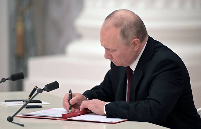 블라디미르 푸틴 러시아 대통령이 21일 러시아 모스크바에서 우크라이나 동부에서 러시아가 지원하는 두 개의 분리 지역을 독립 법인으로 인정하는 법령을 포함한 문서에 서명하고 있다./로이터 연합뉴스