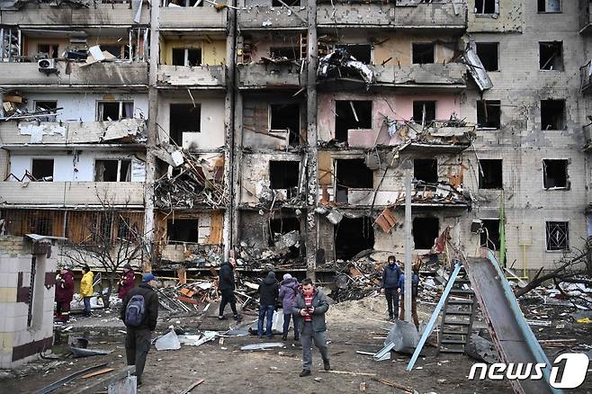25일(현지시간) 우크라이나 수도 키예프 교외의 코쉬차 거리의 러시아군의 폭격을 받은 건물 앞에서 우크라이나 시민들이 잔해를 살피고 있다. © AFP=뉴스1 © News1 포토공용 기자