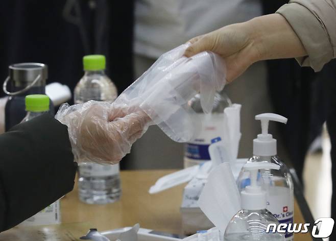 제20대 대통령선거 사전투표 첫날인 4일 서울 종로구 청운효자동사전투표소에서 시민들이 투표에 앞서 비닐장갑을 건네받고 있다. 2022.3.4/뉴스 © News1 송원영 기자