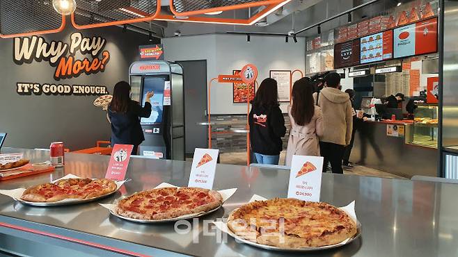 ▲10일 노브랜드 피자 대치점 테스트 매장 내부. 선반에는 노브랜드 피자의 대표 메뉴 투 머치 페퍼로니(1만5800원)피자와 A사 (2만5500원)와 B사(2만4900원)의 페퍼로니 피자가 놓여있다. (사진=백주아 기자)