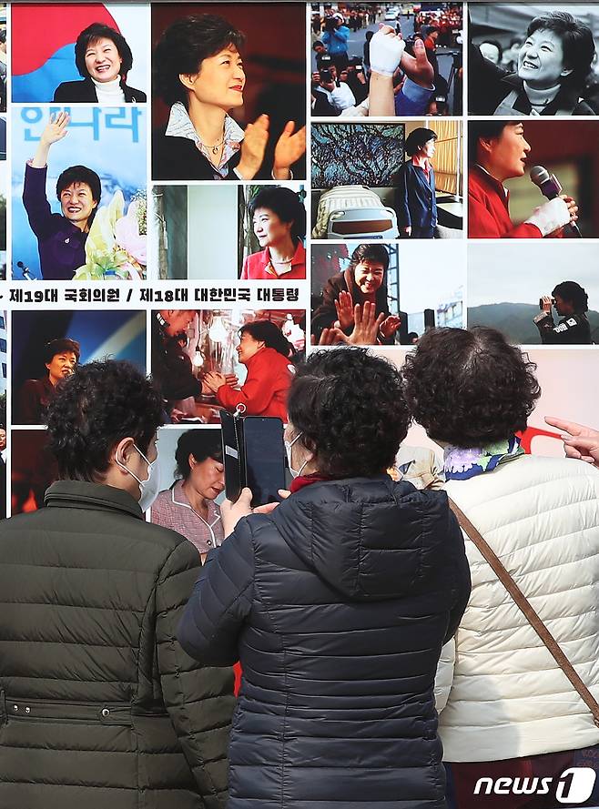 박근혜 전 대통령 귀향과 입주를 하루 앞둔 23일 오후 지지자들이 사저 앞 게시대에 전시된 박 전 대통령 사진을 살펴보고 있다. 2022.3.23/뉴스1 © News1 공정식 기자