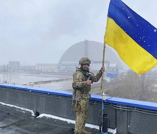 체르노빌 원자력발전소 건물에 우크라이나 깃발을 세운 한 병사의 모습. 사진=AP 연합뉴스