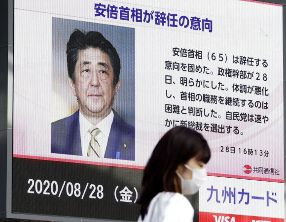 아베 신조 일본 총리가 전격 사임을 발표한 28일 쿠후오카에서 속보를 알리는 뉴스 전광판 앞을 시민이 지나가고 있다.후쿠오카 AP 연합뉴스