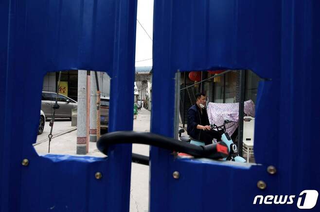 11일 (현지시간) 코로나19 봉쇄령이 내려진 중국 베이징의 자물쇠가 채워진 펜스 내 주거 지역에서 주민이 스쿠터를 타고 있다. © AFP=뉴스1 © News1 우동명 기자
