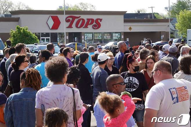 15일(현지시간) 총기난사 사건이 발생한 미국 뉴욕주(州)의 슈퍼마켓 '탑스'(TOPS) 앞에 시민들이 모여있다. 이 사건으로 10명이 숨지고 3명이 다쳤다. © AFP=뉴스1 © News1 김예슬 기자