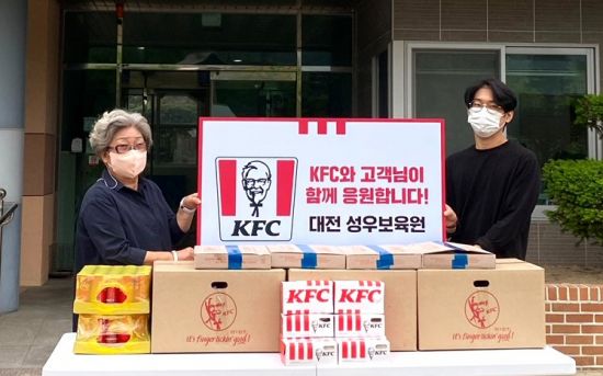 KFC는 대전 성우보육원에 치킨 등 간식 50인분을 기부했다고 16일 밝혔다. 사진은 지난 13일 대전 성우보육원에서 간식 전달식을 진행하는 김익자 성우보육원장(왼쪽)과 고객 김유민 씨.