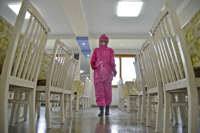 16일(현지시간) 북한 평양에서 전신보호복을 착용한 한 방역 담당자가 식당 바닥에 소독약을 뿌리고 있다. [로이터]