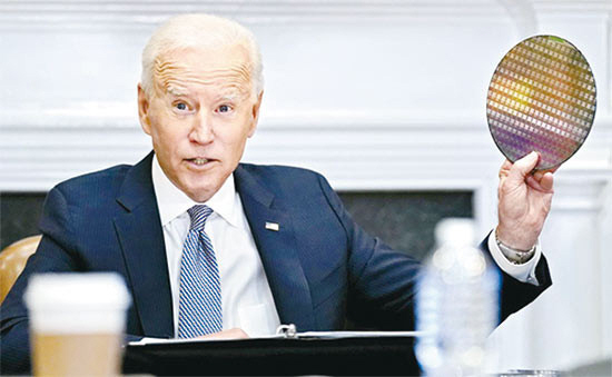 조 바이든 미국 대통령이 지난해 4월 반도체·자동차 업계 19개사 경영진을 상대로 백악관에서 진행한 반도체 영상 회의에서 반도체 재료인 실리콘 웨이퍼를 들어 올리고 있는 모습.