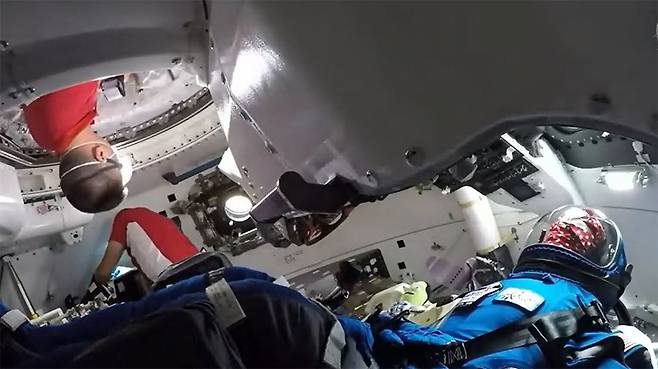 국제우주정거장에 체류 중인 나사 우주인인 로버트 하인스와 키엘 린드그렌이 보잉의 스타라이너로 들어가 조종석에 앉아 있는 ‘로켓조종사 로지(파란색 우주복)’를 환영하고 있다./NASA