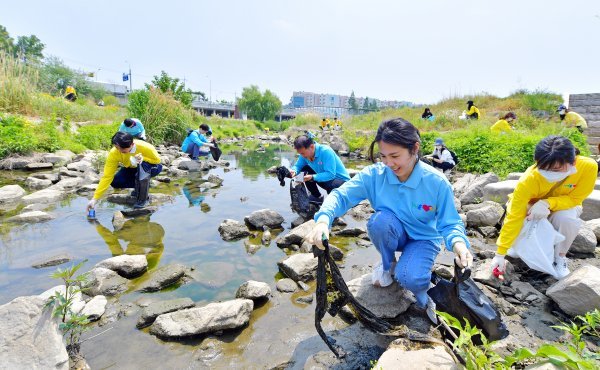 휴일을 맞아 지역환경 정화에 참여한 위러브유 회원들이 탄천변 구석구석을 살피며 쓰레기를 수거하고 있다. 사진제공 | 위러브유