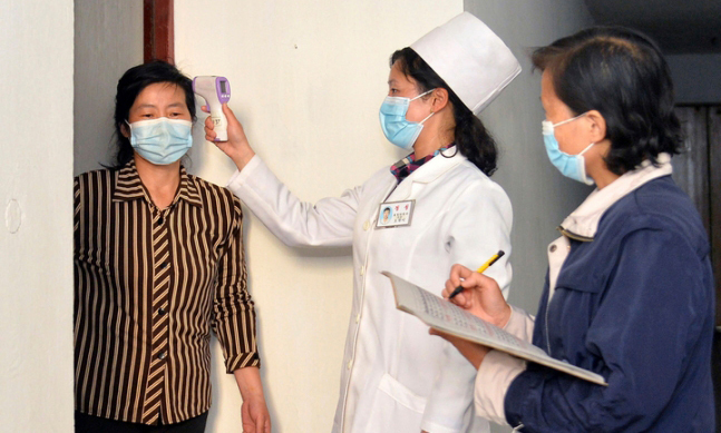 지난 17일 북한 의료 관계자들이 코로나19 확산을 막기 위해 평양 주민의 체온을 점검하고 있다. 평양=AP/뉴시스