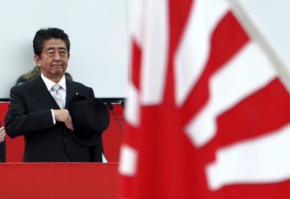 아베의 역주행 -  아베 신조 일본 총리가 자위대의 한 사열식에서 과거 침략국가 일본을 연상시키는 욱일승천기에 대해 경례를 붙이고 있다.