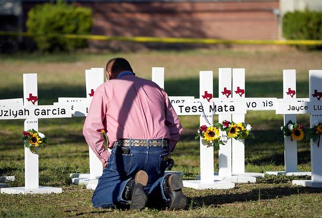 26일(현지시간) 미국 텍사스주 우발데 초등학교 인근 추모식에서 한 목사가 십자기 앞에서 기도하고 있다. [로이터=연합뉴스]