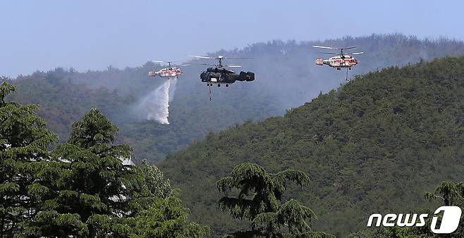 29일 오전 경북 울진군 산불 진화를 위해 출동한 산림청 산불전문진화헬기와 국방부 산불진화헬기가 근남면복지회관 인근 야산에서 산불을 끄기 위해 쉴 새 없이 물을 뿌리고 있다. 2022.5.29/뉴스1 © News1 공정식 기자
