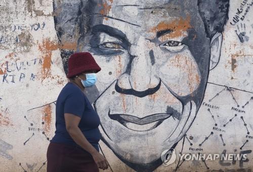지난 4월 넬슨 만델라 벽화 앞을 마스크를 쓴 채 걸어가는 남아공 여성. [AP 연합뉴스 자료사진. 재판매 및 DB 금지]