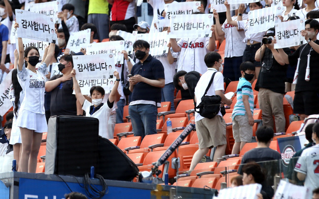 두산 팬들이 25일 잠실구장에서 열린 KIA전에 앞서 한국전쟁 참전용사들이 그라운드에 등장하자 ‘감사합니다’ 문구가 새겨진 클래퍼를 들고 경의를 표하고 있다. 사진제공 | 두산 베어스