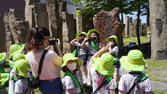 경주엑스포대공원을 방문한 아이들이 자연사 박물관 앞 공령조각위에 앉아 기념사진을 찍고 있다. [사진=경주엑스포대공원]